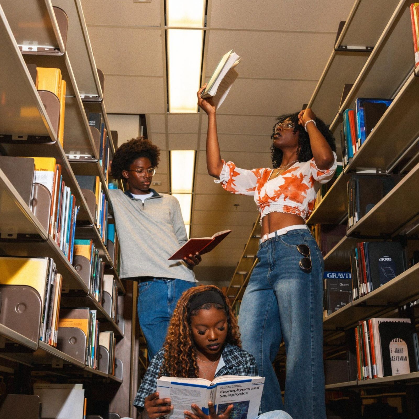 Ever College Station student living apartments Three young people studying between bookshelves in a library.
