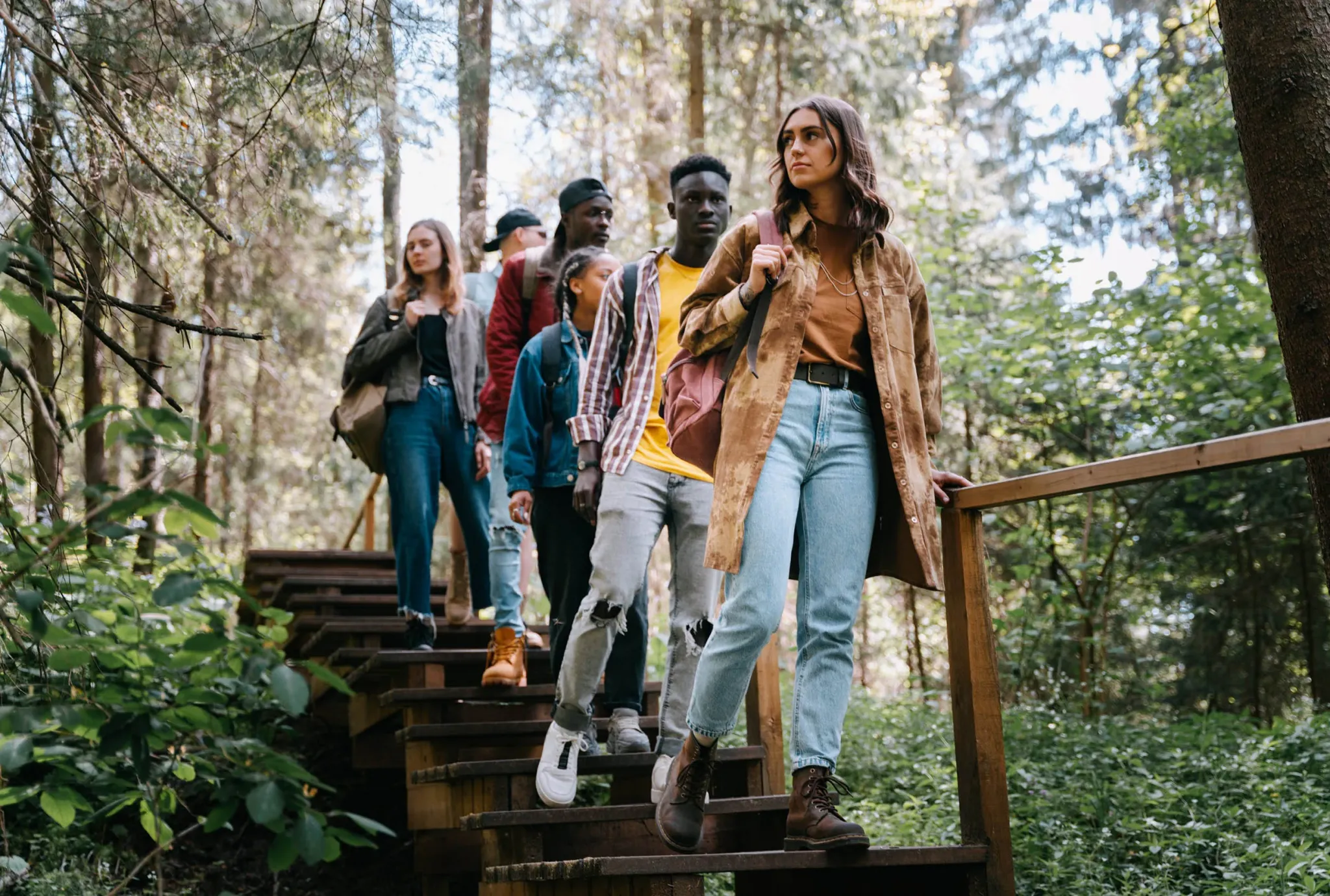 College friends walking together on a nature trail down wooden steps