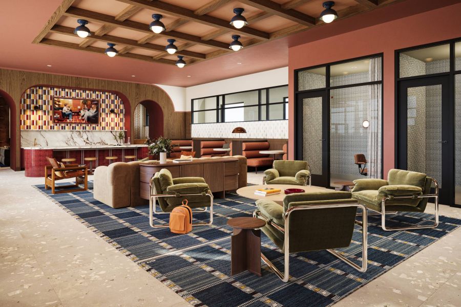 Ever College Station student living apartments Modern lounge with green chairs, blue rug, marble bar, booths, and warm lighting in a spacious room.