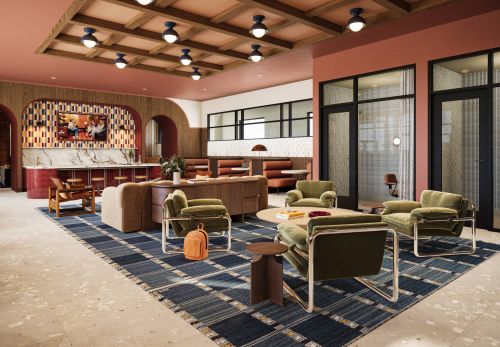 Ever College Station student living apartments Modern lounge with green chairs, blue rug, marble bar, booths, and warm lighting in a spacious room.