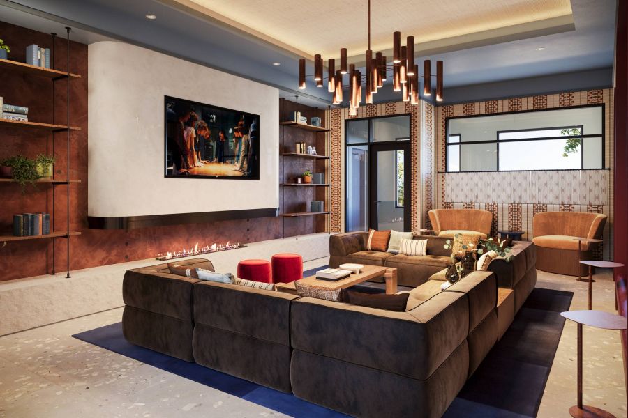 Ever College Station student living apartments Modern living room with a large sectional sofa, wall-mounted TV, shelves, fireplace, and stylish lighting.
