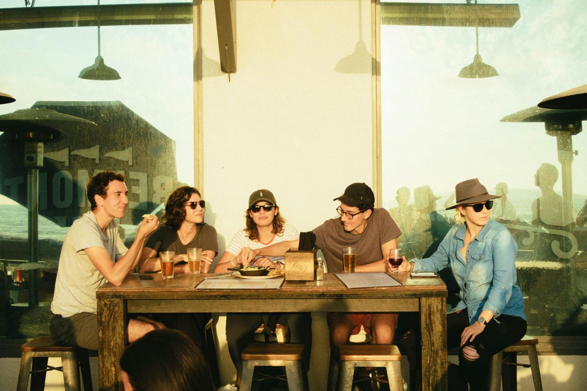 Group of college friends sharing drinks and laughs at an outdoor Northgate restaurant near Texas A&M campus