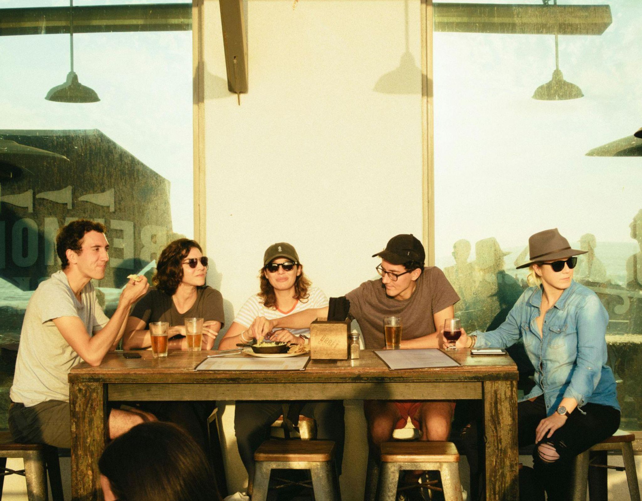 Group of college friends sharing drinks and laughs at an outdoor Northgate restaurant near Texas A&M campus