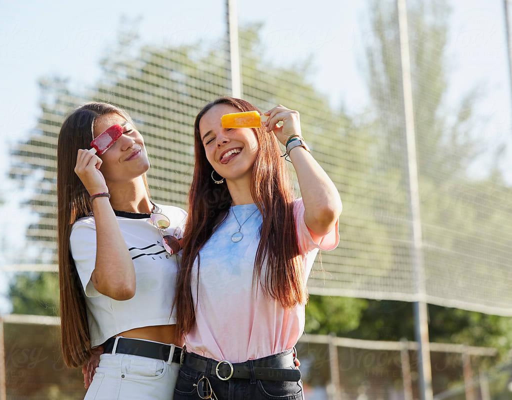 Two Texas A&M students smiling outdoors with popsicles near off-campus housing in Northgate College Station