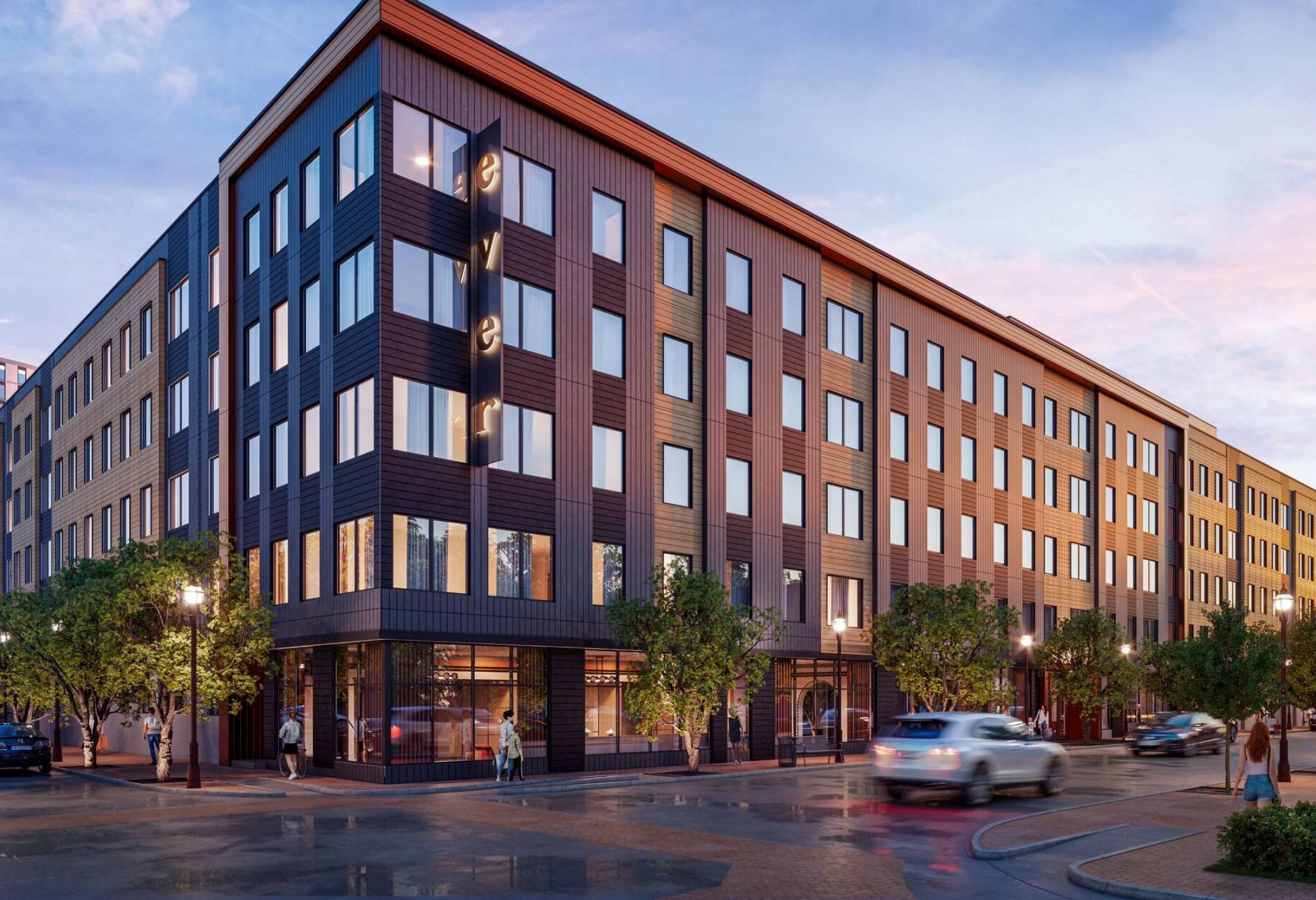 Ever College Station student living apartments A modern, four-story apartment building with large windows and street-level shops at sunset.